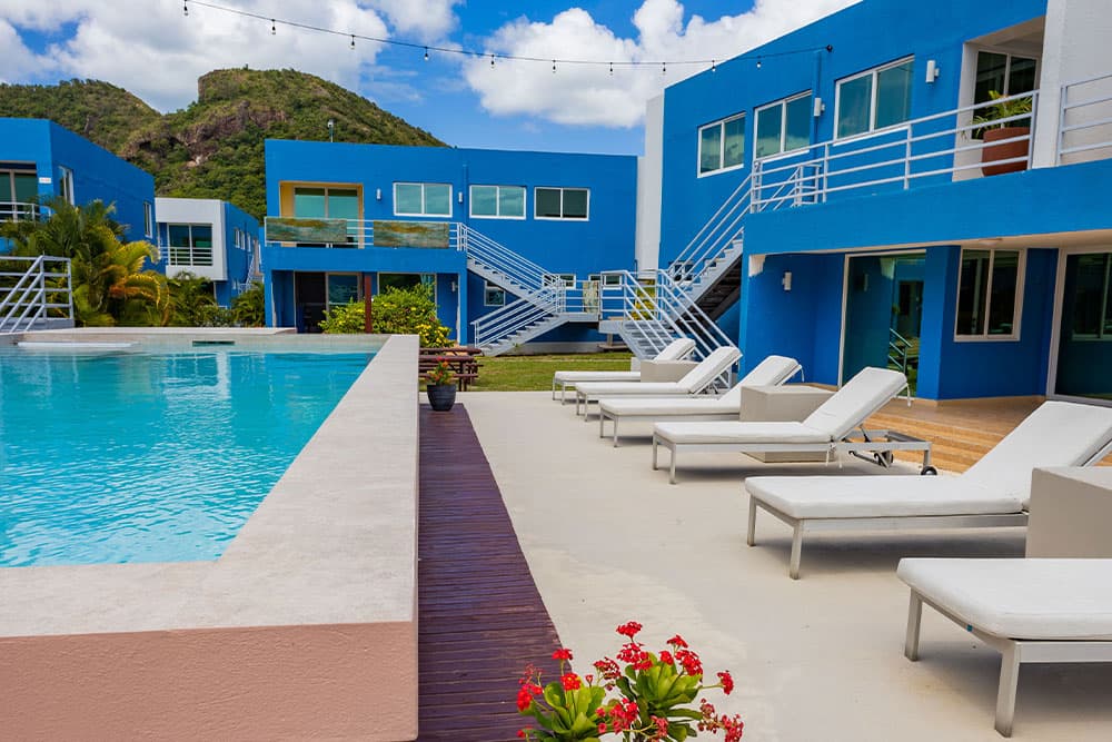 Inviting pool with lounge chairs and blue buildings in background.